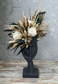 a vase filled with flowers and feathers on top of a wooden table