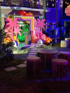 an outdoor area with tables and stools in front of a building decorated with neon lights