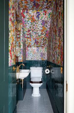 a toilet and sink in a small room with colorful wallpaper on the walls above it