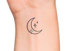 a small crescent tattoo on the wrist with stars and moon in the sky above it