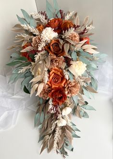 an arrangement of flowers and leaves on a white surface