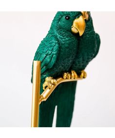 a green parrot perched on top of a golden stick