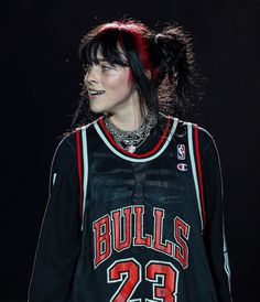 a woman with black hair and piercings on her face is wearing a bulls jersey