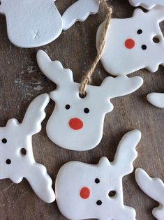 white ceramic ornaments with red nose and antlers hanging on a wooden table, decorated with twine string