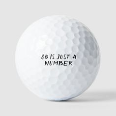 a white golf ball with the words 80 is just a number on it's side