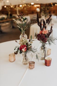 A table at a wedding reception with bud vases that are filled with fall colored flowers and surrounded by votive candles. Designed and made by the florists at Camrose Hill- an outdoor wedding venue and florist located in Stillwater, MN near Minneapolis. Bud Vases Wedding, Bud Vase Centerpiece, Fall Wedding Reception, Rusting Wedding, Wedding Reception Seating, Autumn Wedding Reception, Wedding Reception Flowers, Fall Wedding Centerpieces, Reception Flowers