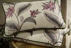 two pillows sitting on top of a wooden table next to a vase with purple flowers