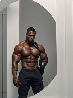 a man standing in front of a white wall with his shirt off and muscles ripped