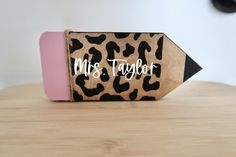 a wooden pencil holder with the word mrs taylor on it and a pink eraser