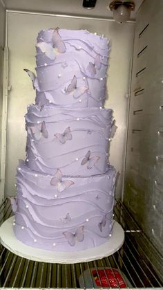 there is a large purple cake with butterflies on it in the refrigerator, ready to be eaten