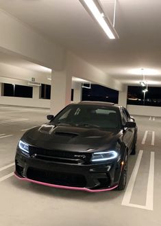 a black car is parked in a parking garage with its hood up and lights on