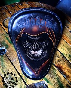 a black leather motorcycle seat with a skull on the front and words, shampoos