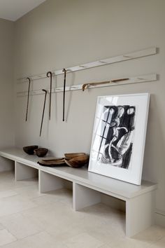 a white shelf with some items on it and hooks hanging from the wall behind it