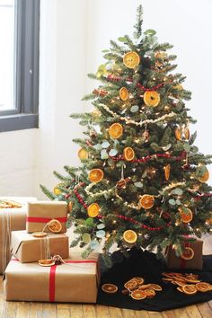 a small christmas tree with orange slices on it and presents under the tree next to it