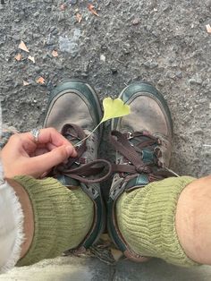 the person is tying their shoelaces to a small green leaf on the ground