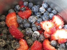 strawberries and blueberries are mixed together in a silver bowl with powdered sugar