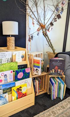 the bookshelf is full of children's books and has a tree in it