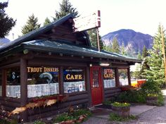 the front of a restaurant with mountains in the backgroung and trees around it