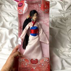 a hand is holding a doll in its package