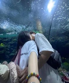 two people kissing in front of an aquarium