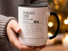 a person holding a coffee mug in front of a christmas tree