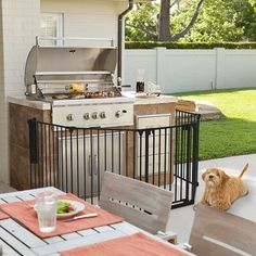 an outdoor kitchen with grill, table and chairs