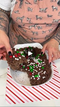 a woman holding a plate with some brownies on top of it and sprinkled with candy