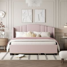 a pink bed in a white room with two pictures on the wall and a chair