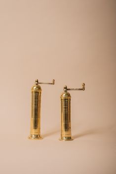 two brass salt and pepper shakers on a white background with the top off to the side