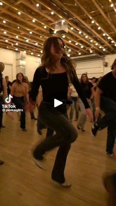 a group of people are dancing in a dance studio with lights on the ceiling and wood floors