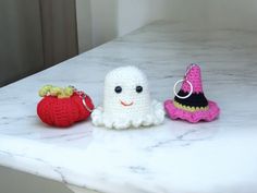 three small crocheted items sitting on top of a white marble counter next to each other