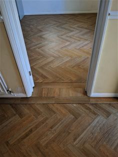 an empty room with wood flooring and white trim on the door, looking into another room