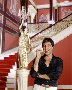 a man standing in front of a stair case next to a statue and red stairs