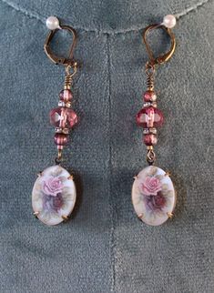 Beautiful and feminine antique gold earrings with 6x8mm translucent burgundy crystal beads, 3mm Czech glass raspberry beads, and 13mm x 18mm pendants with pink and burgundy roses on a white background with a matte finish. These earrings are 2.5" long and 13mm wide.  Free shipping in the USA! Your purchase will be well packaged for shipping and arrive gift packaged. Will ship USPS First Class next day after payment, excluding Sundays and holidays. Includes tracking. Returns: If you are not happy with your purchase, please return within 14 days of purchase for a full refund minus shipping charges. Burgundy Roses, Antique Gold Earrings, Pink And Burgundy, Jacksonville Fl, Rose Earrings, Czech Glass, Antique Gold, Crystal Beads, Beaded Earrings