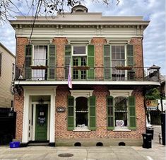 an old brick building with green shutters on the front and second story balconies