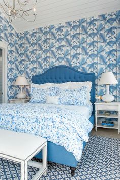 a bedroom with blue and white wallpaper has a large bed in it, along with two lamps on either side of the headboard