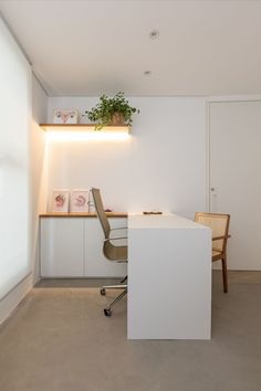 an office with a desk, chair and plant on the shelf in front of it