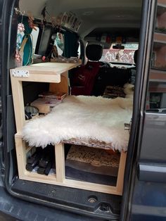 the back end of a van filled with furniture and other items, including an area rug