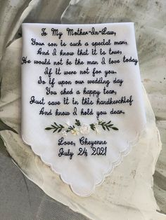 a white handkerchief with embroidered poem on it sitting on top of a cloth covered sheet