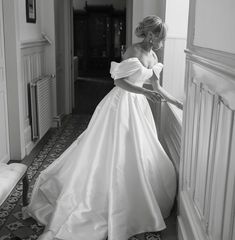 a woman in a wedding dress leaning against a wall with her hand on the door