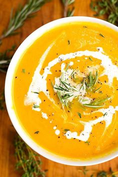 a white bowl filled with carrot soup and garnished with herbs