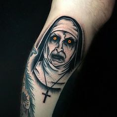 a tattoo with a nun holding a cross on it's left arm and eyes glowing in the dark