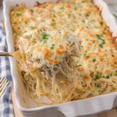 a casserole dish with chicken and cheese in it on a wooden table next to a fork