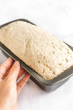 a person holding a loaf of bread in their left hand and pressing it on the right