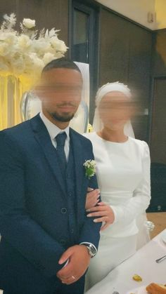 a man in a suit and tie standing next to a woman wearing a wedding dress