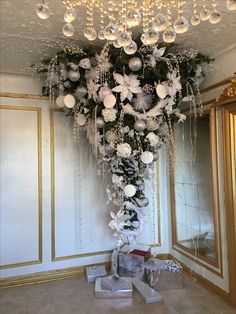 a chandelier hanging from the ceiling in a room with white and silver decorations