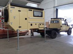 an off - road vehicle is parked next to a truck in a warehouse with other vehicles