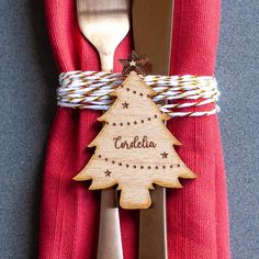 a wooden christmas tree ornament on top of a red napkin with silverware