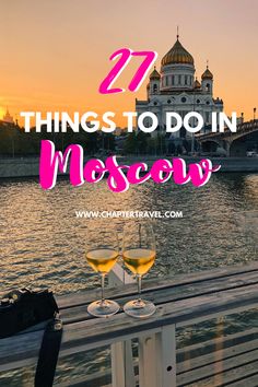 two glasses of wine sitting on top of a wooden table next to the water with text overlay that reads 27 things to do in moscow