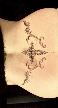 the back of a woman's stomach with an intricate tattoo design on her left side